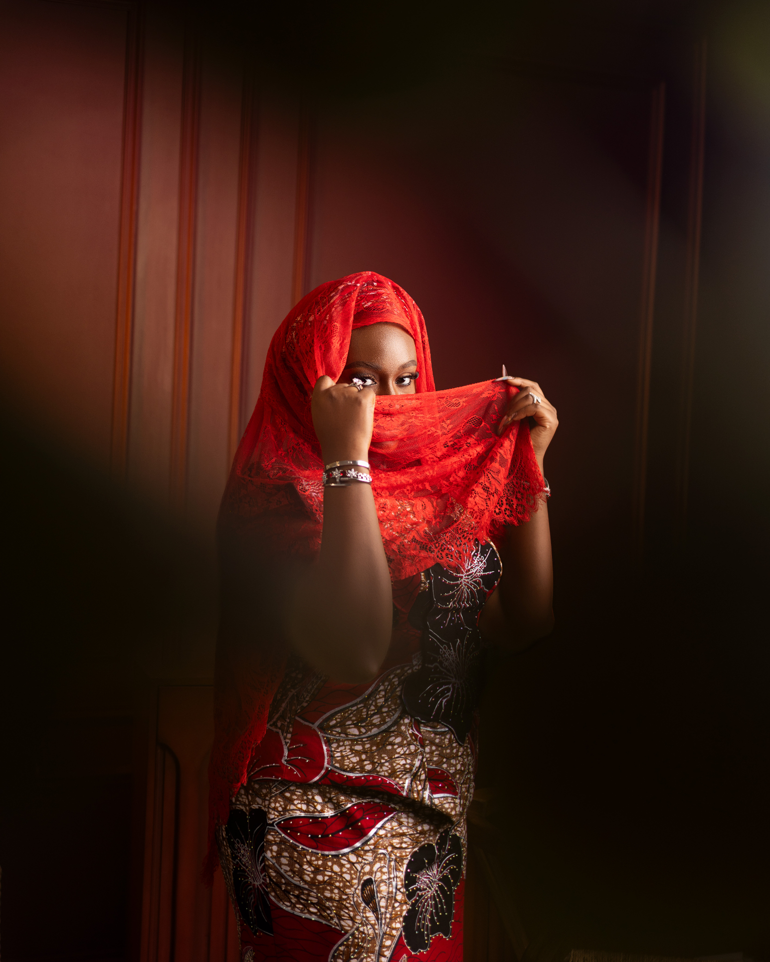 Bride in red lace veil and ankara dress with bangles and rings